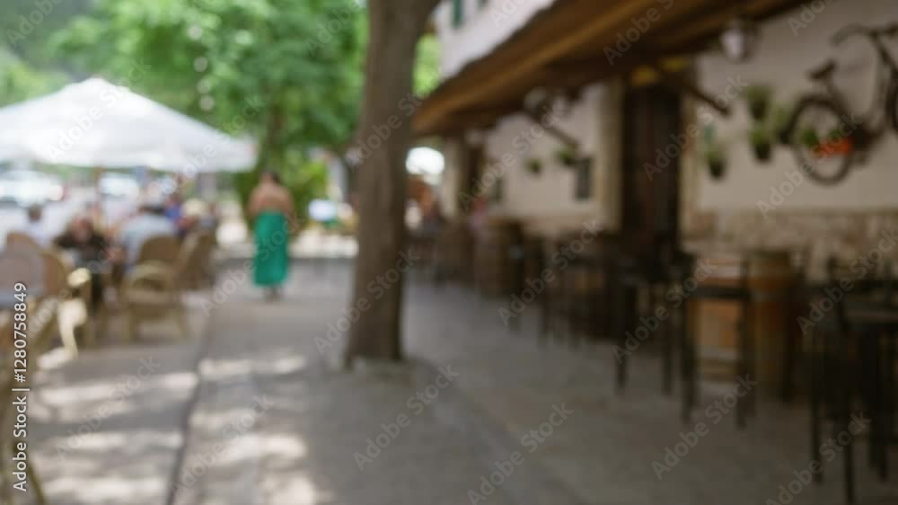 Woman walking along an outdoor cafe in mallorca with a blurred background creating a bokeh effect, people sitting outside in a relaxed ambiance. Woman walking along an outdoor cafe in mallorca with a blurred background creating a bokeh effect, people sitting outside in a relaxed ambiance.