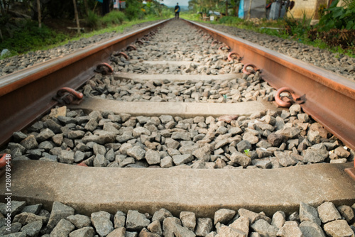 A close-up shot of a train track (rel kereta api), highlighting the metal rails, ties, and surrounding gravel, showcasing the intricate details of the railway system