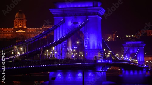 Witness the enchanting beauty of Budapest at night in this stunning video. The iconic Chain Bridge is bathed in a cool blue light, while the Buda Castle glows in warm yellow tones in the background.