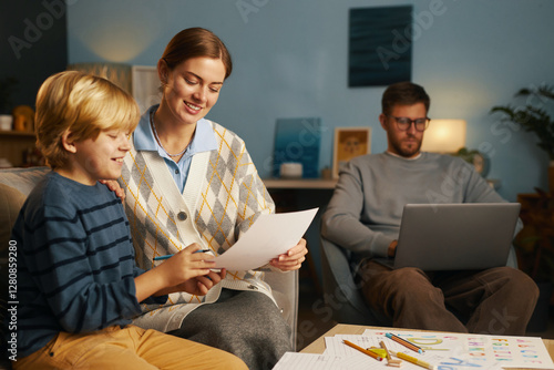 Warm and joyful scene of a family sharing moments at home, mother and child engaging with papers while father working on laptop in background photo