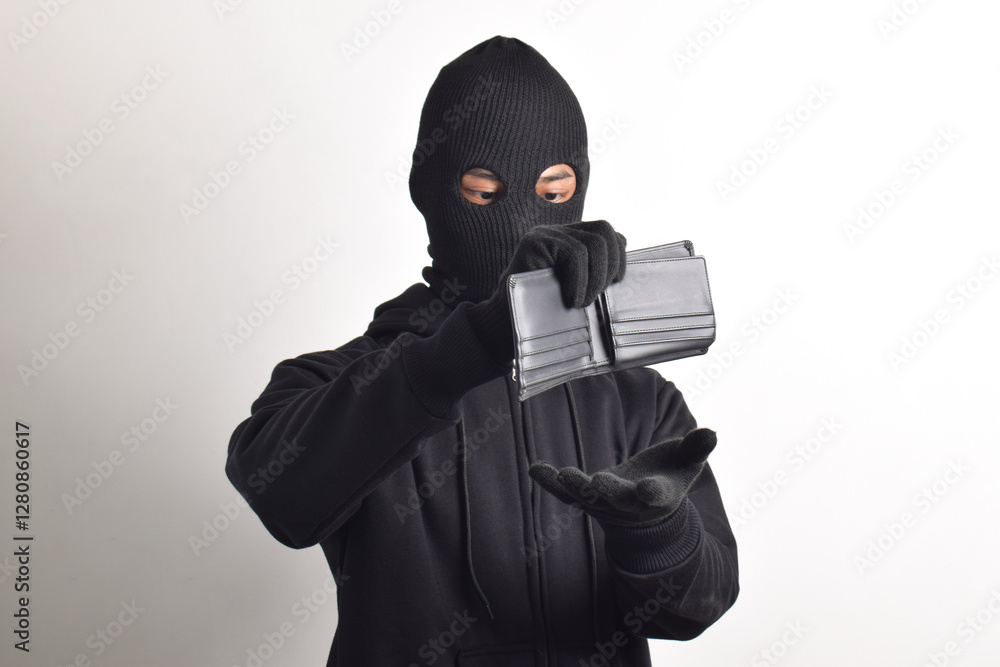 Thief wearing black jacket and mask checking his stolen empty wallet, isolated on white background. Thief wearing black jacket and mask checking his stolen empty wallet, isolated on white background.
