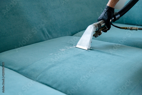 Professional cleaning of a blue sofa using a steam extraction machine in a cozy living room setting