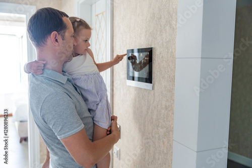 Daughter in her father using tablet panel application for control smart home living. Wireless device controller for home automation IoT on the wall