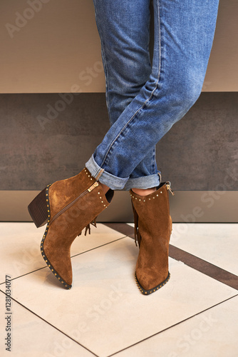 Obraz na płótnie Stylish suede boots, worn with rolled-up jeans, showcasing fringe details and studded accents, modern fashion footwear concept w salonie