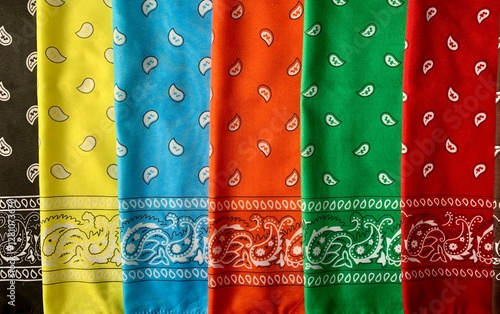 A variety of bandanas in bright colors including yellow, blue, orange, green, and red are arranged neatly, showcasing unique patterns. The setting is lively, ideal for crafting