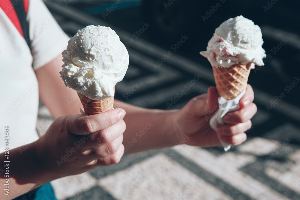 Girl holding two ice cream cones in hands, each topped with a scoop of white ice cream. Sweet summer treat, Perfect for a sunny day