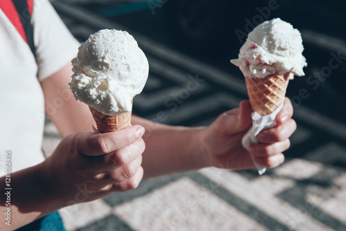 Obraz na płótnie Girl holding two ice cream cones in hands, each topped with a scoop of white ice cream. Sweet summer treat, Perfect for a sunny day w salonie