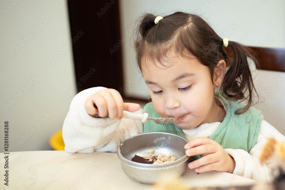 Beautiful multiracial girl eating homemade hot rice with duck meat and vegetables in a cup, sitting at the table in the kitchen. Beautiful multiracial girl eating homemade hot rice with duck meat and vegetables in a cup, sitting at the table in the kitchen.
