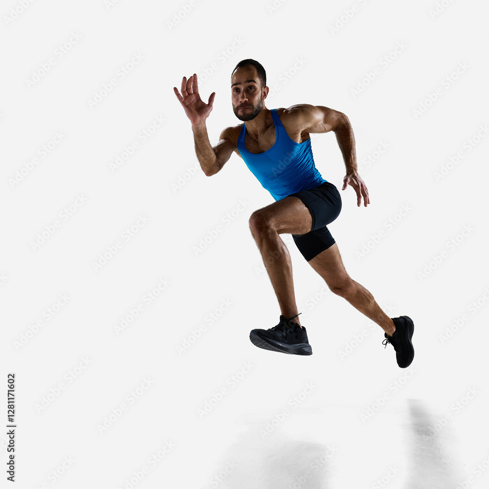 Fototapeta premium Focused man, runner athlete with muscular body in motion, training isolated on white studio background. Concept of sport, competition, endurance, athletics, sportive lifestyle. Copy space