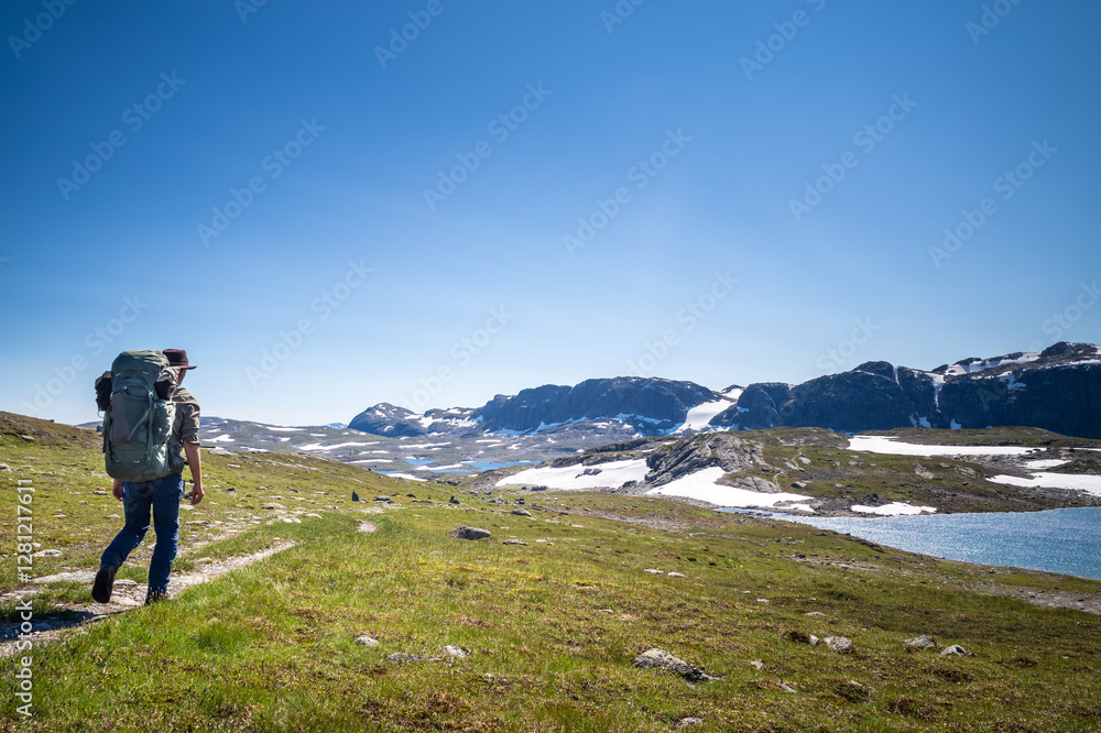 Fototapeta premium Man with a backpack hiking in a mountain area