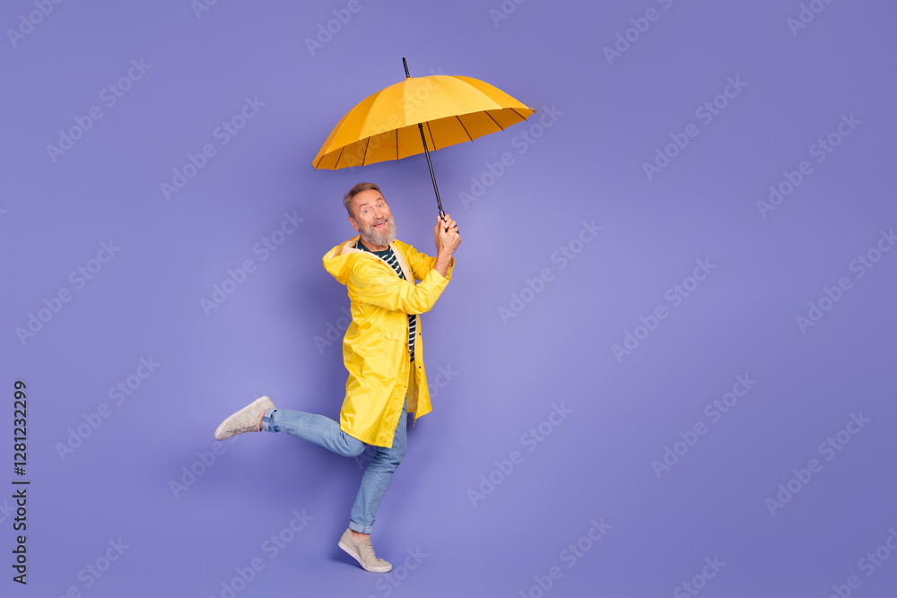 Joyful elderly man in yellow coat jumping with umbrella on violet background showing vibrant leadership and enthusiastic lifestyle Joyful elderly man in yellow coat jumping with umbrella on violet background showing vibrant leadership and enthusiastic lifestyle