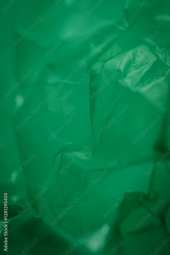 Obraz premium Extreme close up of green empty plastic bag background. The plastic surface is wrinkly and tattered making abstract pattern. Selective focus, shallow depth of field.