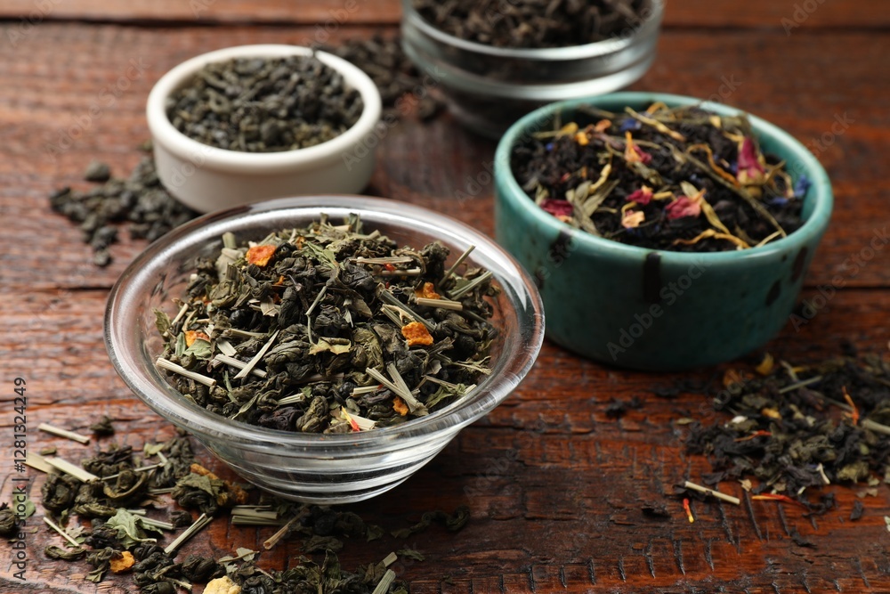 Different dry tea leaves in bowl on wooden table, closeup Different dry tea leaves in bowl on wooden table, closeup
