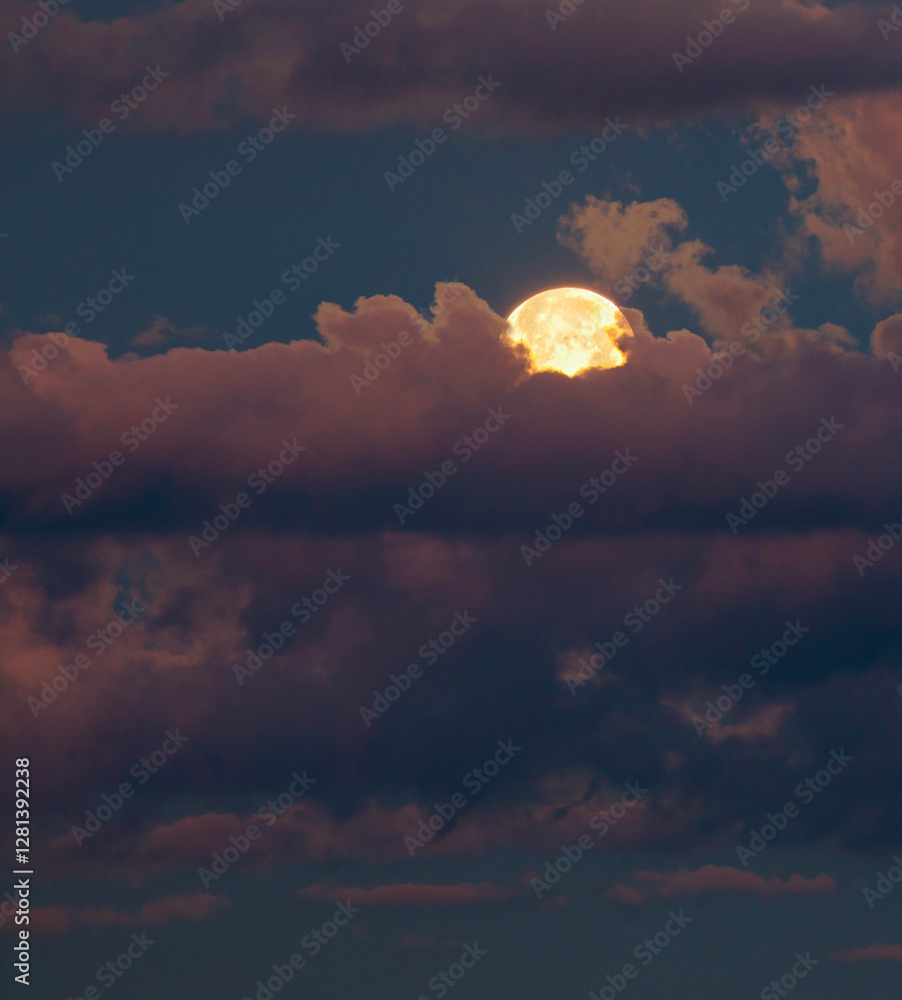 Moon rising between bright clouds