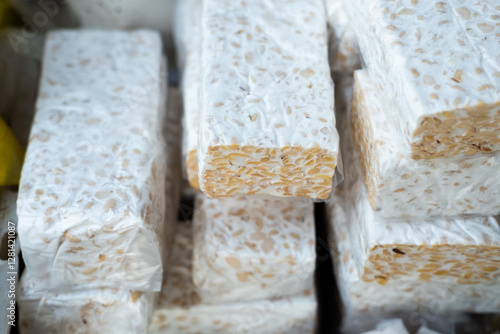 A display of fresh tempeh, highlighting its firm texture, soybean pattern, and natural fermentation process in a market or store setting
