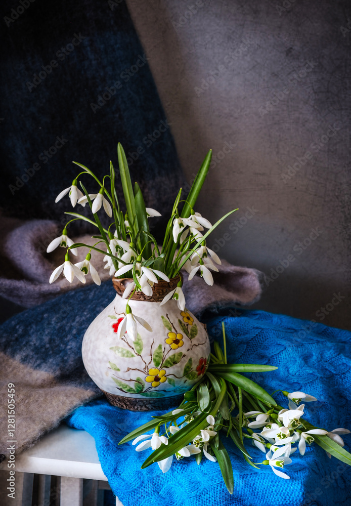 An Elegant Floral Arrangement Placed in a Ceramic Pitcher Surrounded by Beautiful Textiles