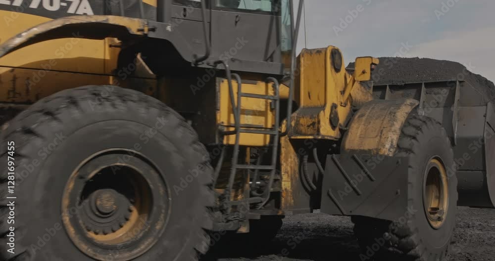 Wheel loader loads coal into wagons. Heavy machinery is working on coal loading at sorting site. Tractor shovels coal with bucket. Sorting and loading of Anthracite. Slow motion shipment coal Wheel loader loads coal into wagons. Heavy machinery is working on coal loading at sorting site. Tractor shovels coal with bucket. Sorting and loading of Anthracite. Slow motion shipment coal