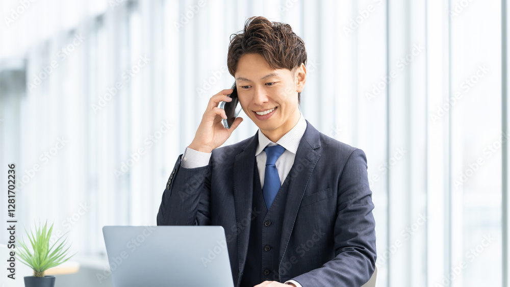 スマートフォンで通話をする笑顔の男性ビジネスマン