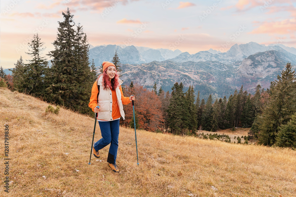 Female hiker using trekking poles walking on mountain trail enjoying Durmitor massif landscape at sunset