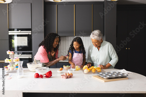 Three diverse generations baking cupcakes in modern kitchen, sharing joyful moments, at home photo