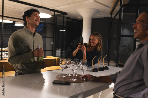 Diverse colleagues celebrating at office, smiling and taking photos with wine glasses photo