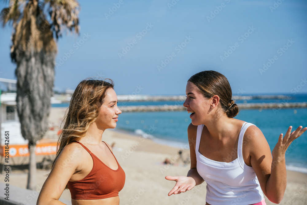 Two young women talking on beach on sunny summer day Two young women talking on beach on sunny summer day