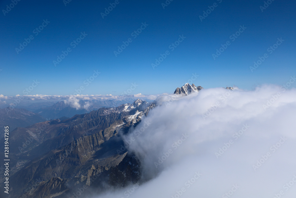 Obraz premium View of the French Alps with a blue sky and clouds covering the peaks above 3000 m above sea level