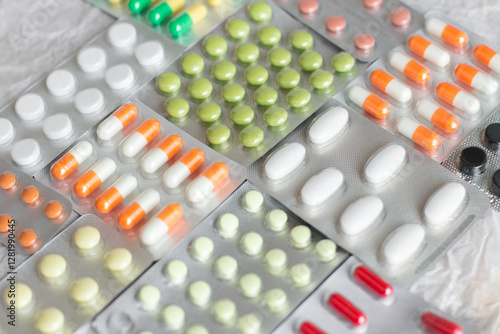 Big pharma metal tablet blister. Multicolor pills medicine. Silver shiny blister with drugs. Transparent capsules in blister pack closeup.