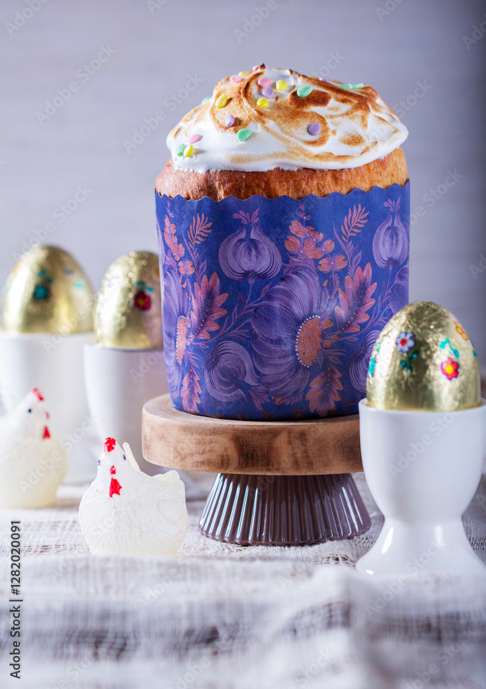 Easter cake, chocolate eggs in gold foil and chicken-shaped candles on a light background.
