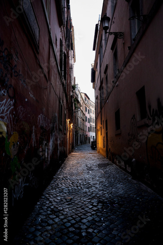 A narrow cobblestone alley in Rome, illuminated by streetlights
