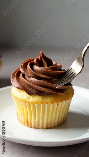 Fork holding a cupcake with chocolate icing on a white plate, dessertinspiration, whiteplate photo