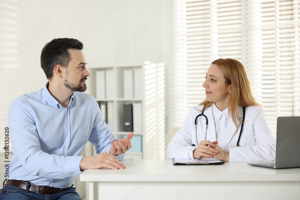 Man having consultation with cardiologist at desk in clinic Man having consultation with cardiologist at desk in clinic