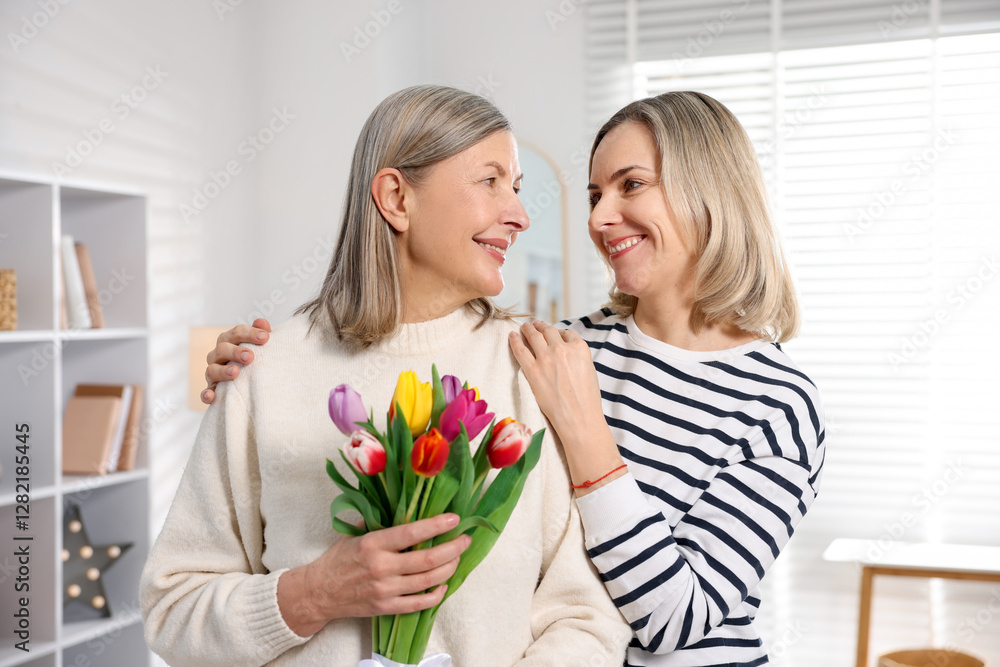 Smiling woman with bouquet of tulips and her daughter at home. Happy Mother's Day Smiling woman with bouquet of tulips and her daughter at home. Happy Mother's Day