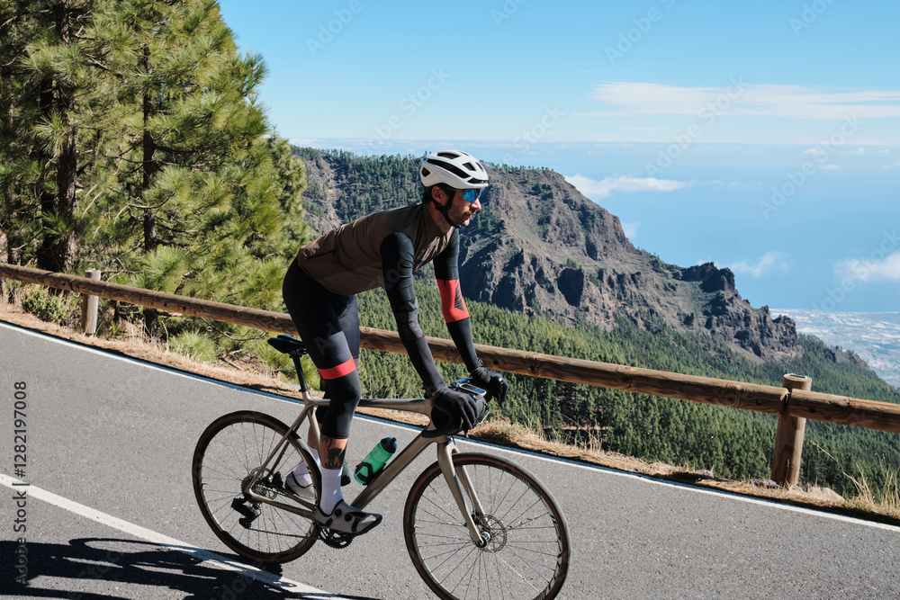 Fototapeta premium Cyclist on a scenic mountain road overlooking the ocean. Stunning landscape and active lifestyle photography. Perfect for travel, sports, or active lifestyle projects.