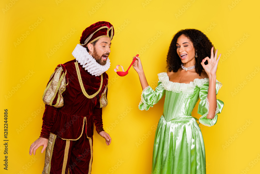 Fototapeta premium Elegant couple in vintage royal costumes on a bright yellow background showcasing playful expressions and classic historical fashion