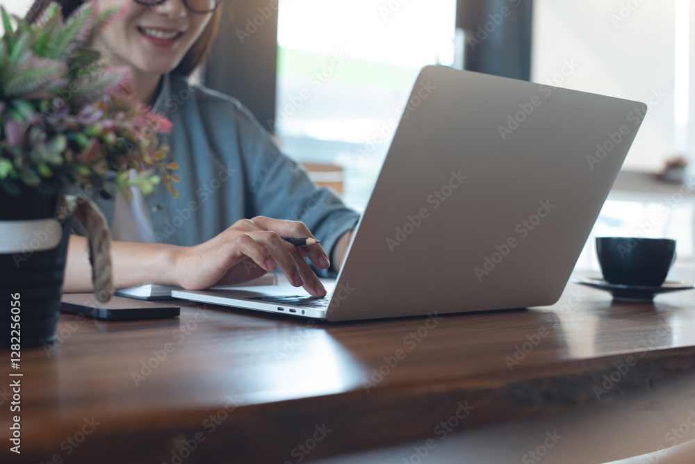 Happy woman sitting in coffee shop, online working on laptop computer, planning work project. Young asian entrepreneur working on laptop, surfing the internet at home office. Student studying online Happy woman sitting in coffee shop, online working on laptop computer, planning work project. Young asian entrepreneur working on laptop, surfing the internet at home office. Student studying online