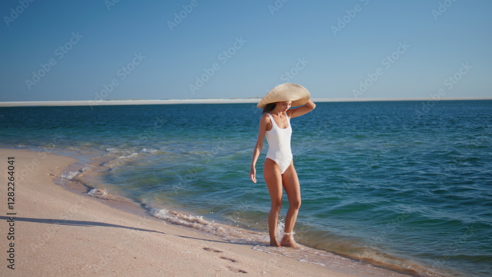 Relaxed lady stepping waves wearing straw hat. Carefree woman walking beach Relaxed lady stepping waves wearing straw hat. Carefree woman walking beach