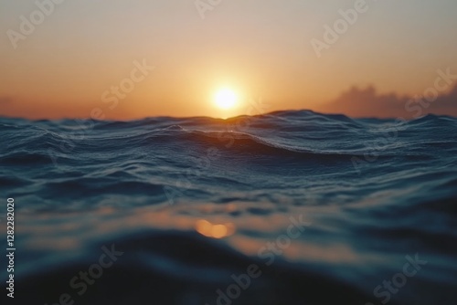 Sunset reflecting on ocean waves creates a serene atmosphere at the shoreline with gentle ripples