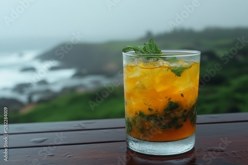 Obraz na płótnie Freshly made citrus cocktail resting on a wooden table with a coastal view in the background during an overcast day w salonie