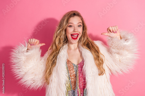 Young stylish woman in a fur coat with energetic gestures against a bright pink background photo