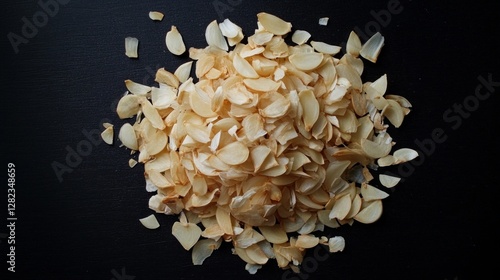 Heap of dried garlic slices on black background for culinary use photo