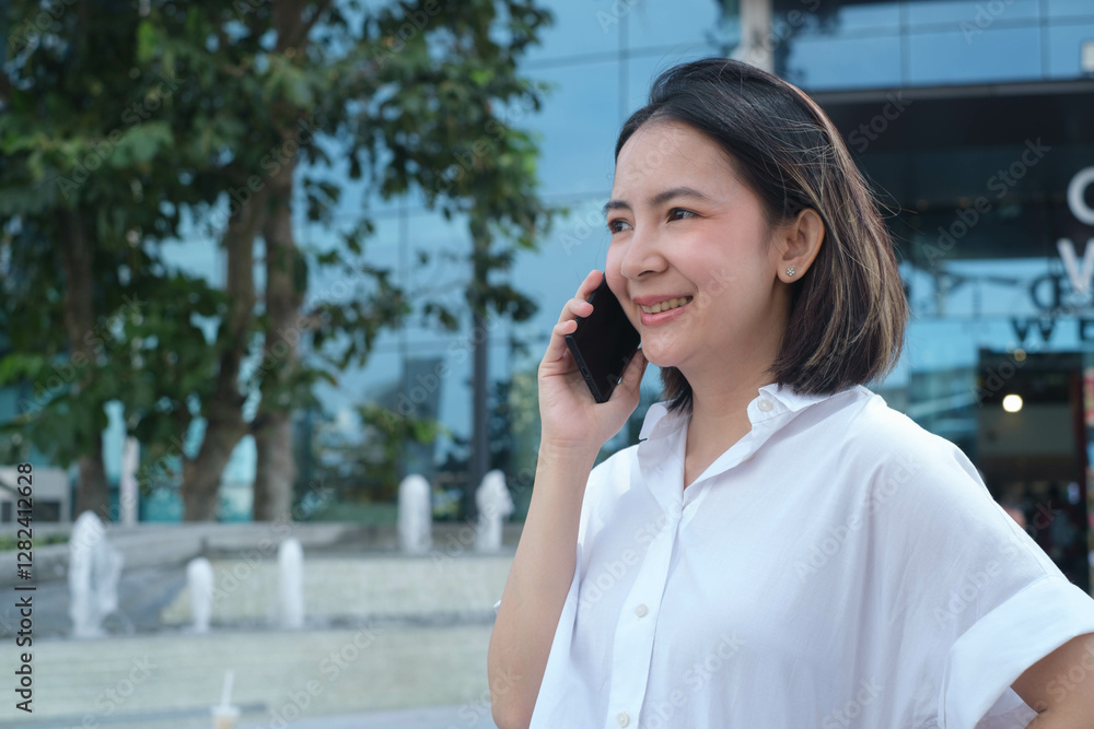 Confident businesswoman in a white shirt using a smartphone outside a modern building, surrounded by greenery and fountains, smiles happily. Confident businesswoman in a white shirt using a smartphone outside a modern building, surrounded by greenery and fountains, smiles happily.