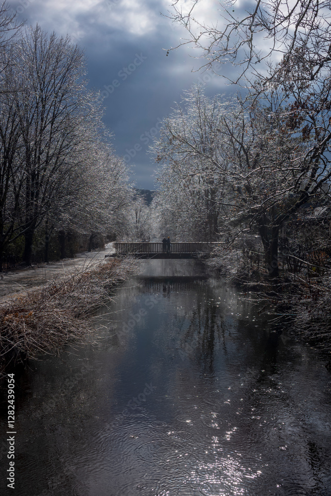 Vistors walk the paths of the Delaware Canal Trail during a cold winter day as the branches of trees glisten in the sunlight after an ice storm.