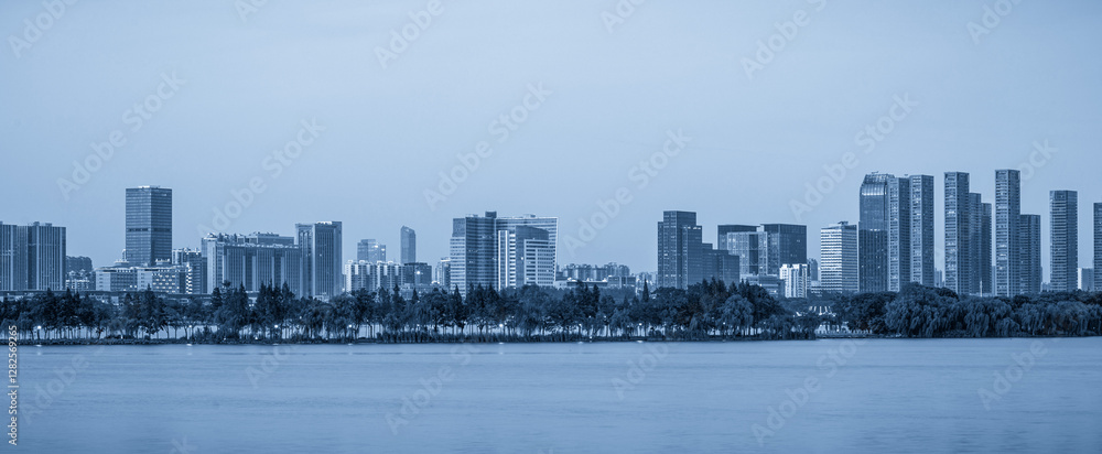 Obraz premium Serene Urban Skyline Reflection: A Panoramic View in Tranquil Blue