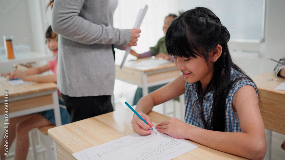 Elementary school students are sitting in the classroom at school and doing final exams in mathematics Elementary school students are sitting in the classroom at school and doing final exams in mathematics
