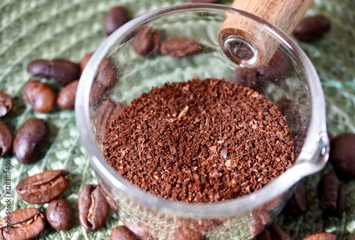 Wallpaper Mural Close up grounded brown aromatic coffee organic dry drink ingredients in small transparent cup bowl object isolated on horizontal green textured table background with coffee beans decorations. Torontodigital.ca