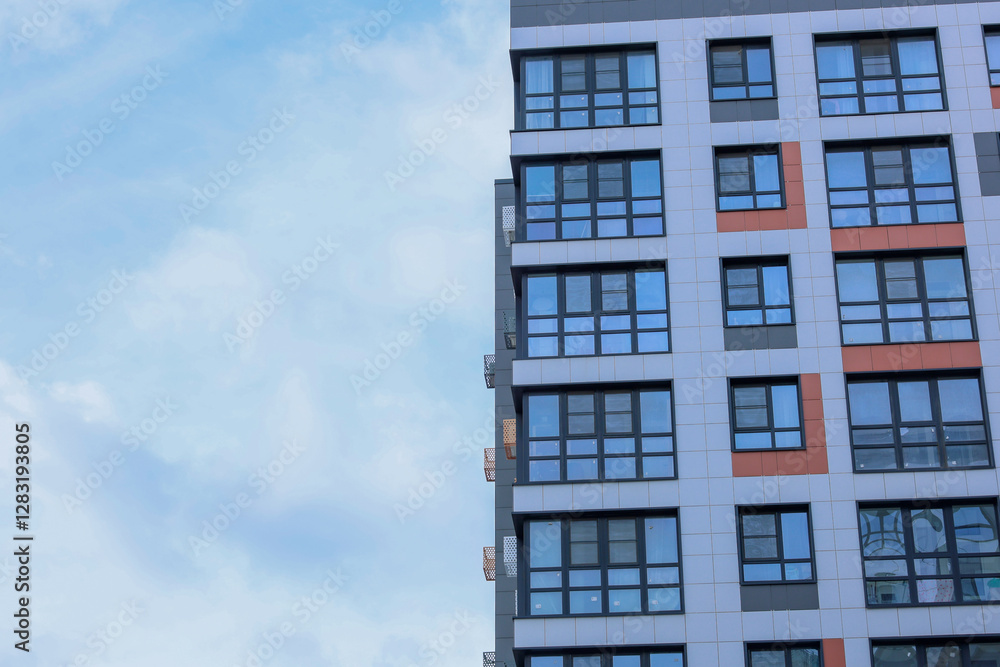 The concept of modern architecture, residential complex, apartment buildings for living. On the right, a close-up of a multi-storey, multi-apartment residential building in gray and white tones with The concept of modern architecture, residential complex, apartment buildings for living. On the right, a close-up of a multi-storey, multi-apartment residential building in gray and white tones with