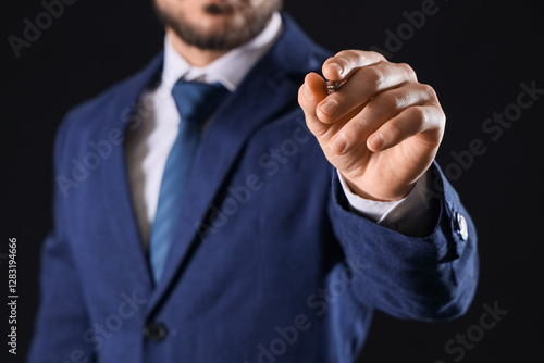 Businessman writing on dark...