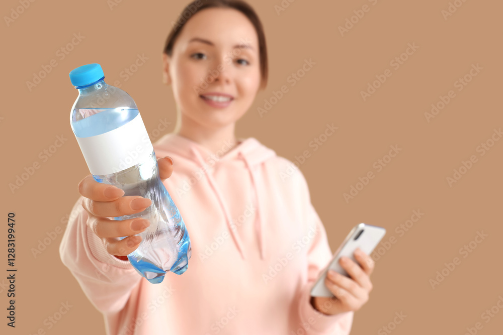 Young woman with bottle of water and mobile phone on beige background Young woman with bottle of water and mobile phone on beige background