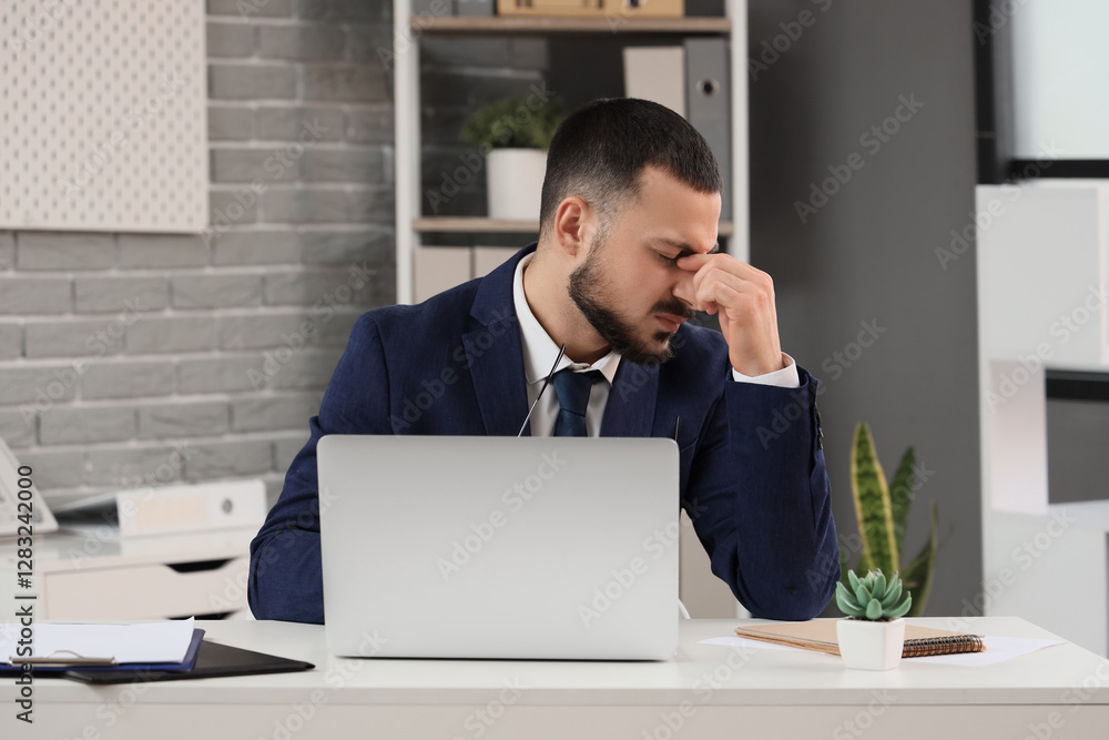 Young businessman feeling unwell at table in office Young businessman feeling unwell at table in office